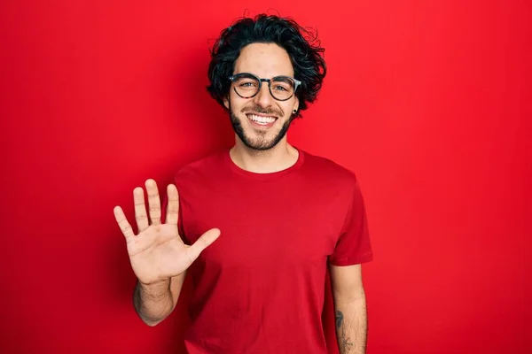 自信と幸せ笑顔ながらシャツや眼鏡を身に着けているハンサムなヒスパニック系の男は指番号5で表示され 指摘します — ストック写真