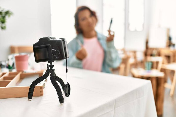 Блогер-латиноамериканец средних лет улыбается, имея видеозвонок в арт-студии.