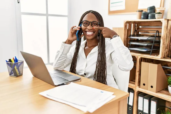 Czarna Kobieta Warkoczami Pracująca Biurze Mówiąca Przez Telefon Wskazując Palcem — Zdjęcie stockowe