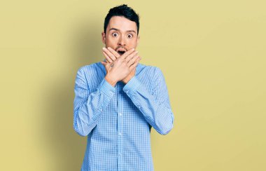 Sıradan iş gömleği giyen İspanyol bir adam ağzı yanlışlıkla elleriyle kapatırken şok geçirdi. gizli kavram. 