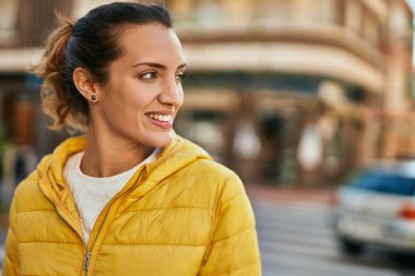 Genç İspanyol kız gülümseyerek şehirde mutlu mesut dikiliyor..