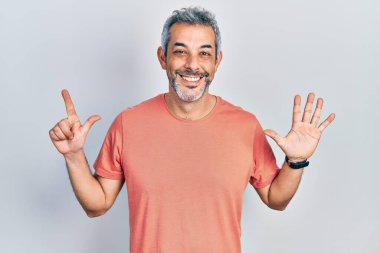 Yakışıklı, orta yaşlı, gri saçlı, sıradan tişörtlü, yedi numaralı parmaklarıyla gösteriş yapan, kendinden emin ve mutlu bir adam.. 