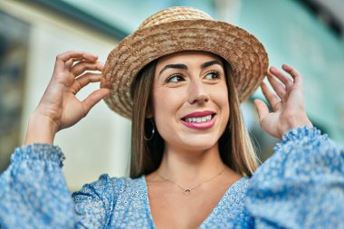 Yaz şapkası takan genç İspanyol kadın şehirde mutlu bir şekilde gülümsüyor..