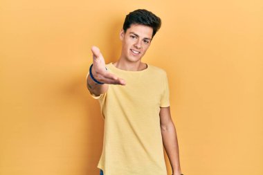 Günlük sarı tişört giyen, neşeli gülümseyen, yardım eli uzatan ve kabul gören İspanyol genç bir adam.. 