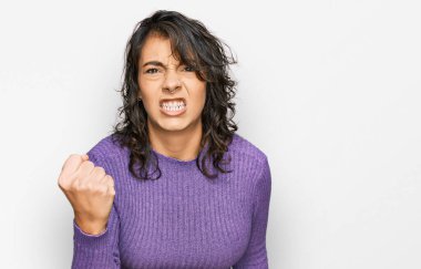 Genç İspanyol kadın rahat kıyafetler giyiyor kızgın ve kızgın yumruğunu kaldırıyor ve öfkeyle bağırıyor. öfke ve agresif konsept. 