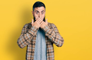 Sıradan tişörtler giyen İspanyol bir adam yanlışlıkla elleri ile ağzını kapatırken şok oldu. gizli kavram. 