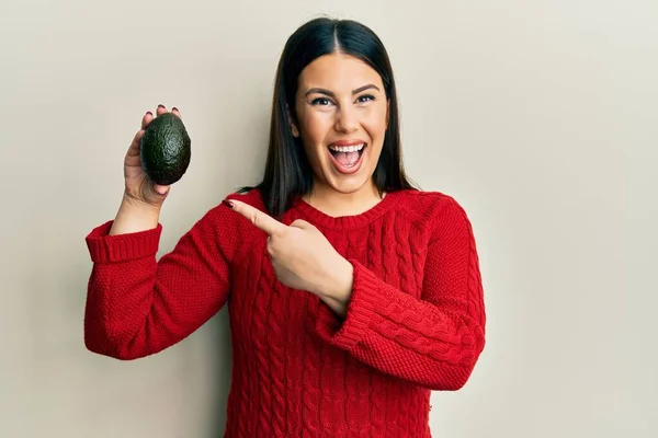 Vacker Brunett Kvinna Håller Avokado Ler Glad Pekar Med Hand — Stockfoto