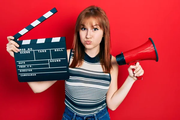 Ruiva Jovem Segurando Vídeo Filme Clapboard Megafone Soprando Bochechas Com — Fotografia de Stock