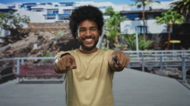 Neşeli bir şehir caddesindeki kameraya gülümseyen adam berrak mavi gökyüzü altındaki modern binalarla pozitif enerji ve dostluk yayıyor..