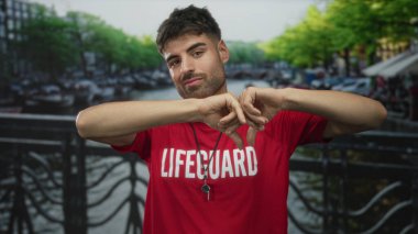 Genç İspanyol cankurtaran güneşli şehir caddesinde elleri ile kalp şekli yapar; sıcak şefkatli sevgi aşk.