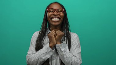 Canlı yeşil bir arka plana gülümseyen, gözlüklü, çizgili gömlekli, mutluluk ve enerjiyi ifade eden bir kadın..