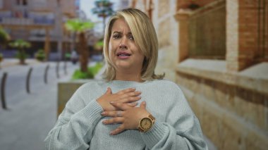 Kadın şehir caddesinde, bulanık vitrinler ve taş duvarlar arasında, korku ve panik içinde elini göğsüne koyuyor..