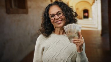 Üniversite ayininin önünde elinde Rus rublesi banknotlarıyla gülümseyen bir kadın ilginç bir finans ve akademi karışımı sergiliyor..