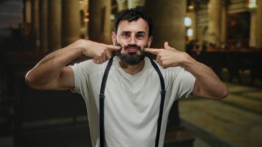 Sakallı İspanyol bir adam, katolik bir kilisede, jartiyer ve beyaz gömlek giyerek neşeli ve anlamlı bir atmosferi ön plana çıkaran neşeli ve şaşırtıcı bir ifade sergiliyor..