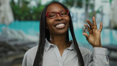 Tatil köyünde elinde havuz başında havuz başında gülümseyen bir kadın açık hava ortamında kripto güveni sergiliyor..