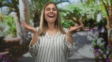 Avuç içleri açık, gözleri parlak bir kadın sıcak güneş ışığı altında ve ormanda sık ağaçlar altında gülümsüyor. Şaşırtıcı bir neşe..