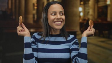 Kilisede neşeli bir şekilde gülümseyen kadın gözlerinde kurabiyeler tutuyor, eğlenceli ve neşeli bir atmosfer yaratıyor..