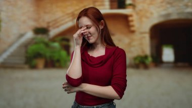 Açık havada başı dertte olan bir kadın şık kıyafetler giymiş canlı bir şehir arka planına karşı, duyguları ve şehir yaşam tarzını yakalıyor..