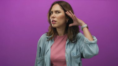 Kot giymiş bir kadın pembe arka planda şaşkınlık içinde kulağını tutuyor. Meraklı, soyutlanmış, hareketli, canlı, etnik bir kadın modeli olduğunu ifade ediyor. Duygularını yansıtıyor..