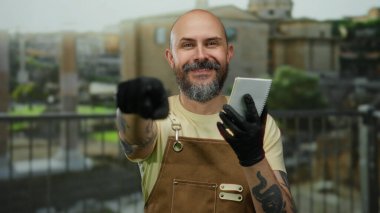 Antik Roma harabelerine karşı elinde defterle açık havada poz veren siyah eldiven ve önlük giyen bir adam, modern modayla tarihi mimarinin bir karışımını örnek gösteriyordu..