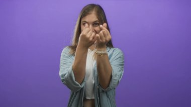 Kot gömlek giyen sarışın kadın stüdyoda gülümserken parmak kalp hareketi gösteriyor..