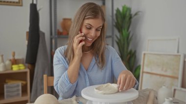 Kadın, parlak modern sanatkar stüdyosunda dönen bir çarkın üzerindeki çamuru dikkatlice şekillendirir; yaratıcı ifade dinginliği.