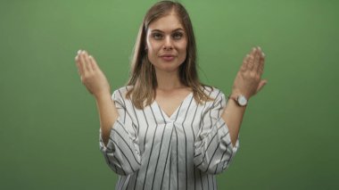Çizgili bluzlu kadın yeşil bir stüdyoda avuçlarını açık tutarak el kaldırır. Şaşırtıcı bir şaşkınlık içindedir..