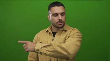 Hardal gömlekli İspanyol adam yeşil stüdyoyu işaret ediyor, azim ve büyüme hırsı odaklanıyor..