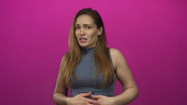 Kadın yüzünü örterken ve parlak pembe stüdyo duvarında el kaldırırken görünür bir şekilde titriyor; korku..