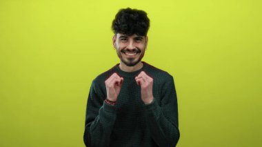 Parlak sarı arka planda gülümseyen genç adam, günlük süveter giyiyor. Parlak ve neşeli bir portre pozuyla mutluluk ve kendine güveni ifade ediyor.