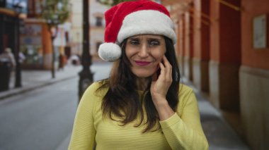 Latin kökenli genç bir kadın, şehir caddesinde diş ağrısı için elleriyle yanağa dokunuyor; diş ağrısı rahatsızlığı.