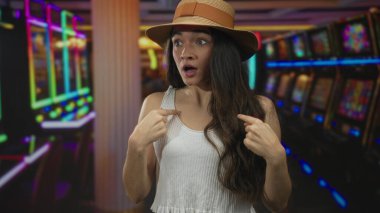 Neon kumarhane binasında iki eli de göğsünü gösteren geniş gözlü bir kadın..