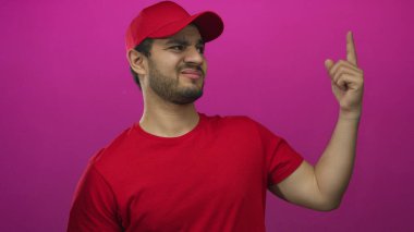 Kırmızı tişörtlü ve şapkalı genç İspanyol teslimatçı parmağını morumsu stüdyoda sallıyor..