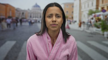 Vatikan St. Peter Meydanı 'nda pembe bornozlu korkmuş bir kadın ve arka planda insanlar var..