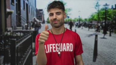 Gündüz vakti güneşli bir şehir sokağında kırmızı gömlekli genç İspanyol cankurtaran el ele tutuşuyor..
