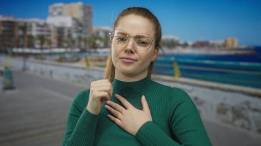 Kadın, yeşil kazak ve gözlük takarak kalp krizi geçirmek için göğsünü öksürüyor ve sıkıyor..