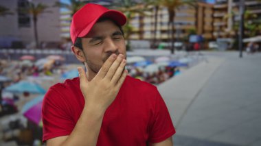 Genç teslimatçı, elleri sokakta güneşli bir sahil geçidinde kalbi şekillendirir; sessiz bir şefkat.