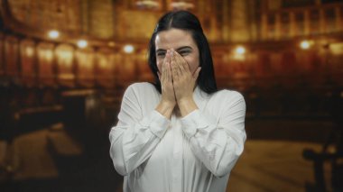 Ilık bir kilisenin içinde sevinçle gülümseyen genç İspanyol kadın beyaz bir gömlek giyiyor, kolları açık coşku ve mutluluğu ifade ediyor..