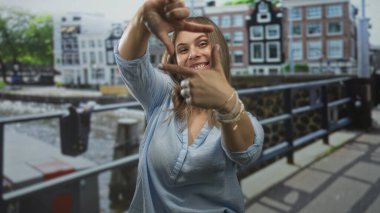 Su ve tuğla evlerin yakınındaki sokakta elleri kanal korkuluğu ile jest yapan kadın..