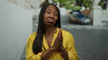 Şehir merkezinde kuşkuculuk taslayan bir kadın. Sarı gömlekli, örgülü saçlı, güneşli bir caddede..