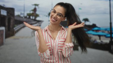Kadınlar yaz güneşli deniz kenarındaki gezintide, plaj şemsiyeleriyle bardakları ayarlar; kaygısız neşe.