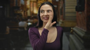 Kilise ortamında etkileyici bir yüzle fısıldayan kadın, arka planda bulanık bir cemaatle süslü iç mekanda neşeli ve canlı bir anı yakalıyor..