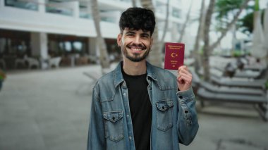 Şehir merkezinde Türk pasaportu taşıyan bir adam modern kasaba sokaklarında seyahat ve kimlik konsepti sergiliyor..