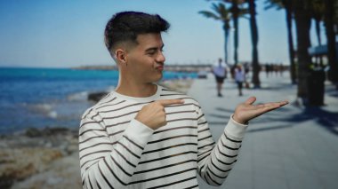 Genç adam deniz kenarındaki gezinti alanında güneşli gökyüzünün altında rahatlık ve rahatlığın esansını yakalıyor..