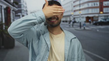 Mavi ceketli ve bronz tişörtlü genç bir İspanyol, şehrin sokaklarında el kaplayan gözleriyle gülümsüyor..