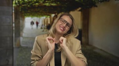 Kendine güvenen sarışın kadın şehir sokaklarında kemerleriyle geziyor modern mimari ortamda gösterişli bir yaşam tarzı ve modaya ayak uyduruyor.