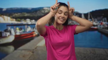 Demirlemiş teknelerin ve güneşli rıhtımın yakınındaki bir limanda boynuzlarını boynuzlayan kadın..