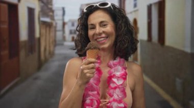 Bikini giyen ve bikini giyen bir kadın eski kasaba sokaklarında gülümseyen orta yaşlı İspanyol bir kadın açık havada yaz neşesini temsil ediyor..