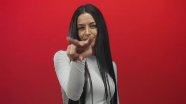 İspanyol kadın, izole edilmiş kırmızı arka planda tetikte olma ve ihtiyatı elden bırakmama uyarısı yapıyor..