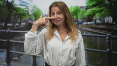 Amsterdam Kanalı caddesinde beyaz gömlek ve nazik bir gülümsemeyle burun buruna gezen bir kadın..